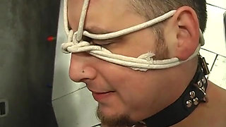 BDSM mistress in thigh-highs ropes dude's collared face and pulls his bound cock