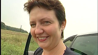 Lovely mature lady blows a guy's cock outdoors near the car